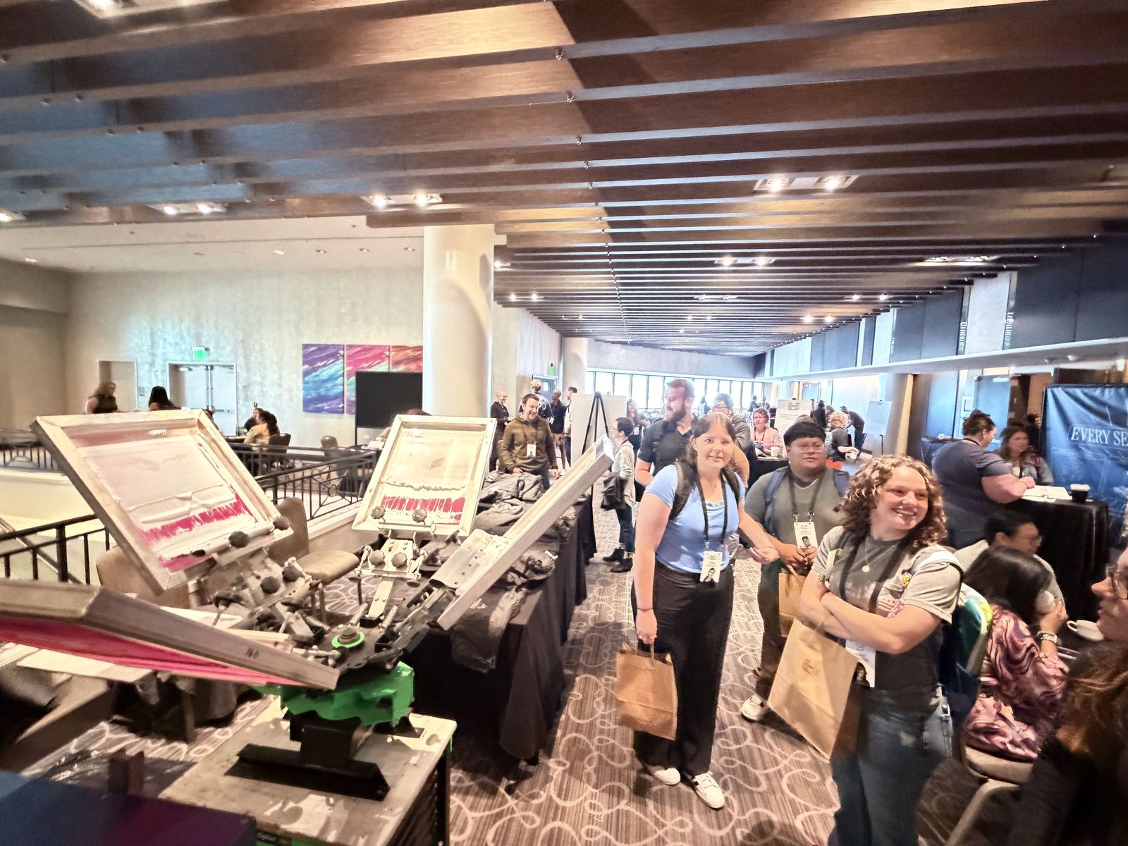 Screen printing stations running onsite printing services in a hotel conference lobby as attendees line up