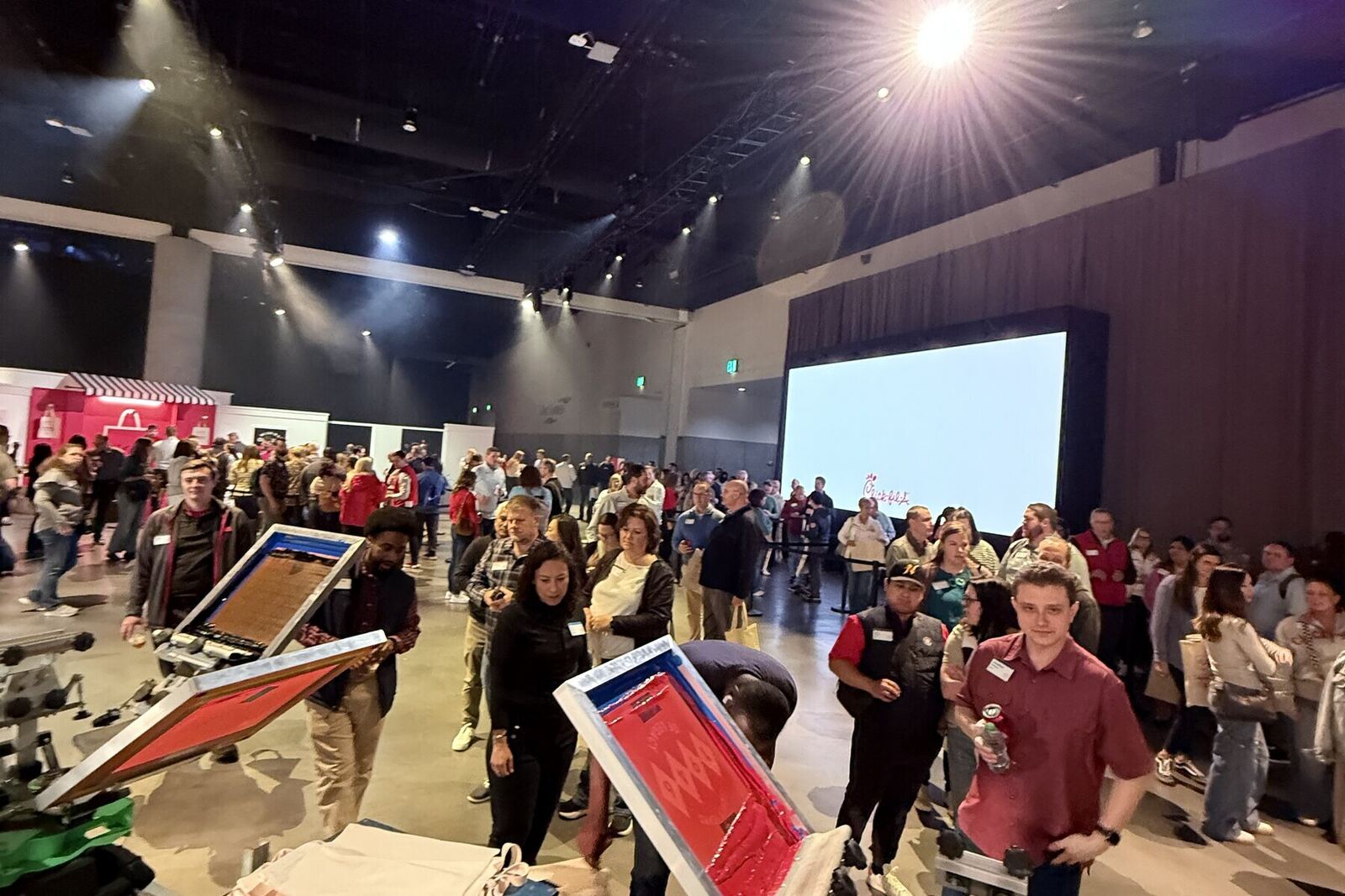 Onsite print crew running presses while an event program plays on the main screen